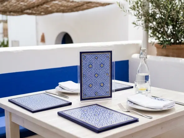 Menus de restaurant à motif zellige bleu sur une table de terrasse dressée, avec assiettes, serviettes et carafe d'eau — Impression menus de restaurant
