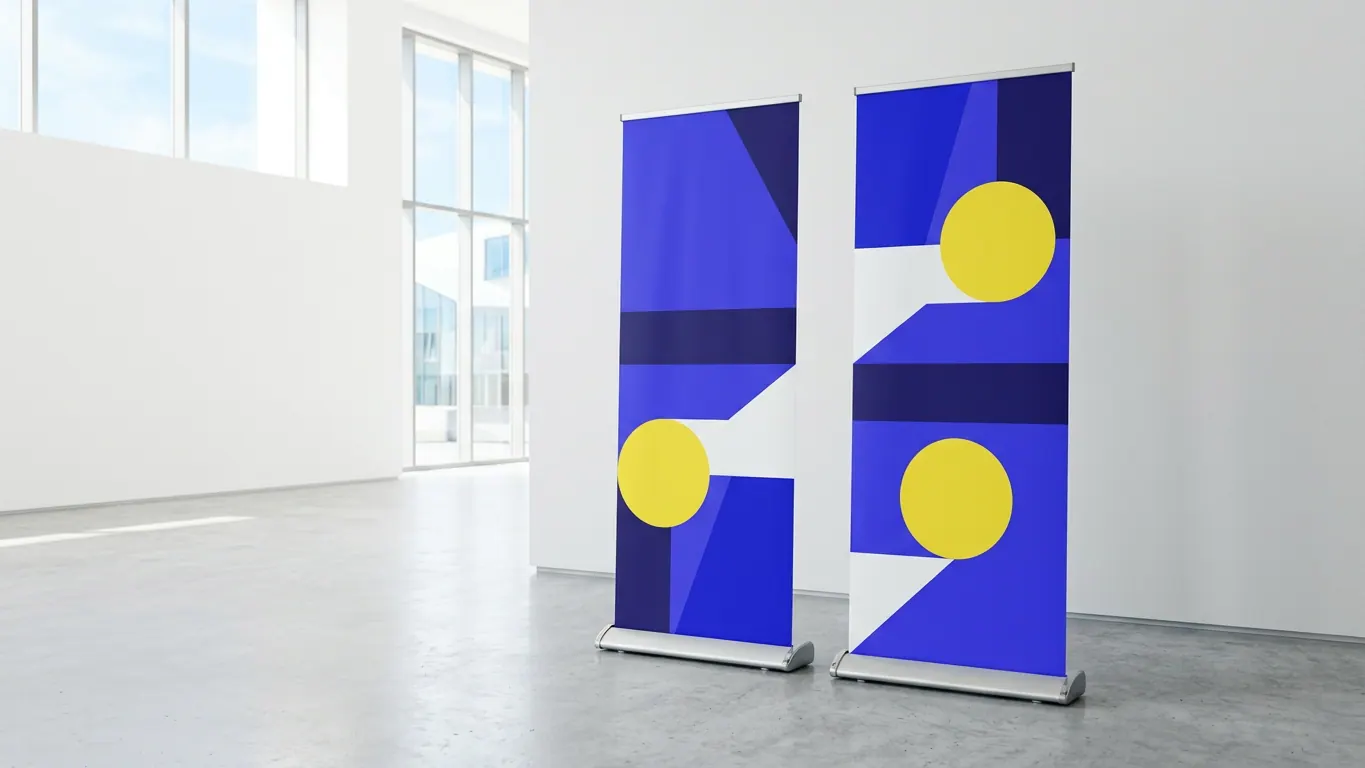Deux roll-up aux visuels géométriques bleus et jaunes sur bases en aluminium dans un hall lumineux — Impression roll-up